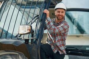 Looking out from the vehicle, smiling. Man is with tractor. Agricultural worker photo