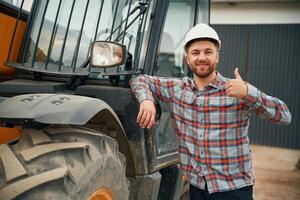 Leaning on, the vehicle. Man is with tractor. Agricultural worker photo