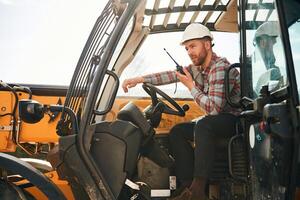 Using radio, talking.. Man is with tractor. Agricultural worker photo