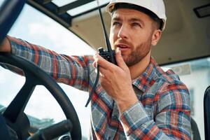Walkie, talkie device, ,conversation, orders. Man is with tractor. Agricultural worker photo
