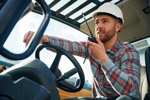 Walkie talkie device,, conversation, orders. Man is with tractor. Agricultural worker photo