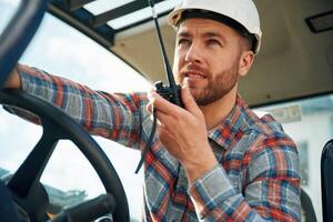 Walkie talkie, device, conversation, orders. Man is with tractor. Agricultural worker photo
