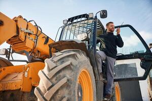 View from, below, using walkie talkie. Man is with tractor. Agricultural worker photo