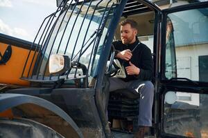 Sitting, in the vehicle. Man is, with tracto..r. Agricultural worker photo