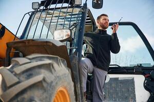 View,, from below, using walkie talkie. Man is with tractor. Agricultural worker photo