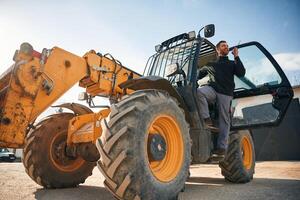 View ,from below, using walkie talkie. Man is with tractor. Agricultural worker photo