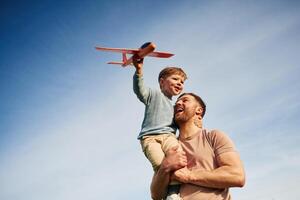 Father is holding son that playing with toy plane. photo