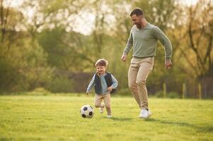 With soccer ball. Happy father with son are having fun on the field at summertime,, photo