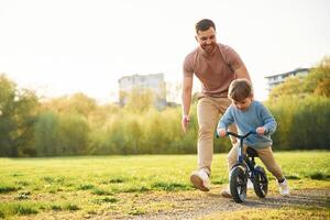 Bicycle, having fun. Happy father with son are on the field at summertime photo
