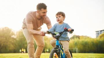 Trying ,the bicycle. Happy father, with,, son are having fun on the field at summertime photo