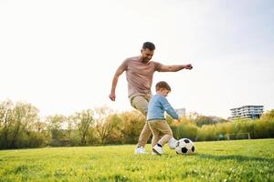 Playing soccer. Happy father with son are having fun on the field at summertime photo