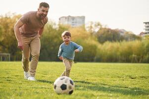Learning to play soccer. Happy father with son are having fun on the field at ,summertime photo