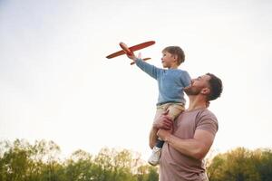 Father is holding son that playing with toy ,plane photo