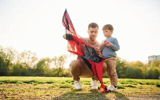 Red,kite. Happy father ,with son are having fun on the field at summertime photo