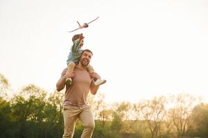 Toy plane, is ,,in the air. Happy father with son are having fun on the field at summertime photo
