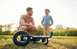 Little, bicycle. Happy father with son are, having fun on the field at summertime photo