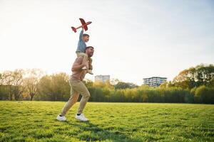 Orange, colored, toy,, plane, playing. Happy father with son are having fun on the field at summertime photo