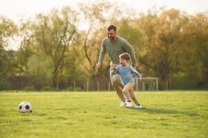 With ,soccer ball. Happy father ,with ,son are having fun on the field at summertime photo