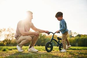 Little bicycle. Happy father with son are ,having fun on the field at summertime photo