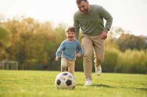 Learning ,to play soccer. Happy father, with son are having fun on the field at summertime photo