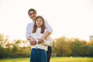 Mother and daughter are standing on the summer field together and smiling photo