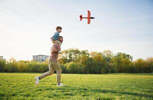 Toy plane, is in the air. Happy father ,with son are having fun on the field at summertime photo