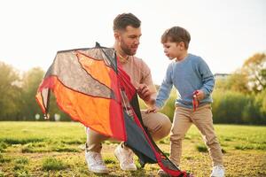 Red kite. Happy ,father with ,son are having fun on the field at summertime photo