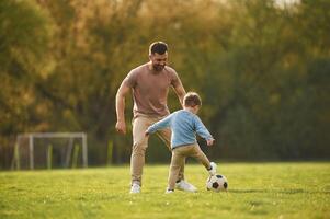 Learning to play soccer... Happy father with son are having fun on the field at summertime photo