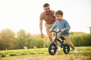 Little bicycle. Happy,, father ,with son are having fun on the field at summertime photo