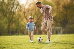 Learning to play soccer., Happy father with son are having fun on the field at summertime photo