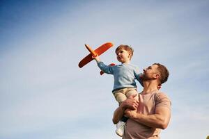 Blue sky with white cloud., Father,, is holding son that playing with toy plane photo