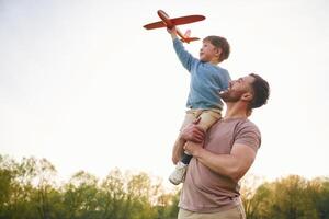 Father is holding son that ,playing ,with, toy plane photo