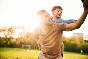 On ,shoulders, with soccer ball. Happy,, father with son are having fun on the field at summertime photo