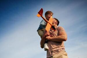 Father is,, holding son that playing with toy plane photo