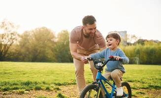 With bicycle, having fun. Happy father with son are on the field at summertime photo