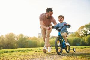 Bicycle, having ,,fun. Happy father with son are on the field at summertime photo