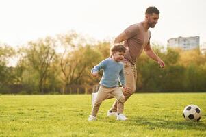 Teaching ,how to play, a, soccer. Happy father with son are having fun on the field at summertime photo