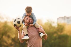Real, football, soccer ball. Happy father with son are having fun on the field at summertime photo