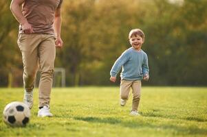 Teaching how to play,, a soccer. Happy father with son are having fun on the field at summertime photo