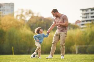 Real football, soccer ball.. Happy, father with son are having fun on the field at summertime photo