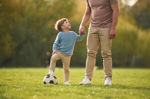 Teaching, how to play, a soccer. Happy father with son are having fun on the field at summertime photo