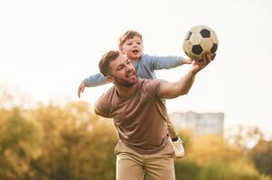 Real football, soccer ball. Happy,, father ,with son are having fun on the field at summertime photo