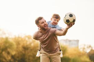 Real football, soccer ball. Happy father, with, son are having fun on the field at summertime photo