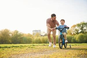 Bicycle,, having fun. Happy father with ,,son are on the field at summertime photo