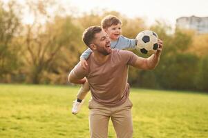 Real football, soccer ball. Happy father ,,with, son are having fun on the field at summertime photo