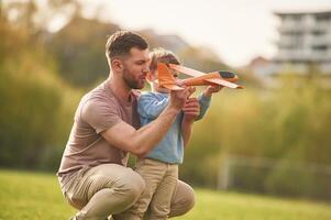 Freedom,,, playing, with toy plane. Happy father with son are having fun on the field at summertime photo