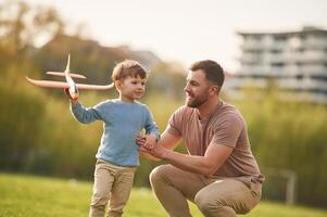 Freedom, playing with toy ,plane. Happy, father with son are having fun on the field at summertime photo