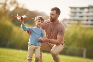 Freedom,, playing with toy plane. Happy father with son are having fun on the field at summertime photo