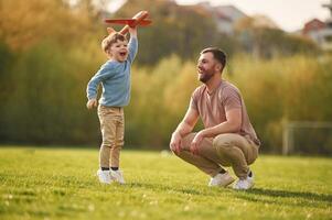 Weekend,, activities. Playing with toy plane. Happy father with son are having fun on the field at summertime photo