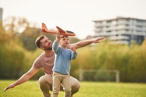 Freedom, playing with ,,toy ,plane. Happy father with son are having fun on the field at summertime photo